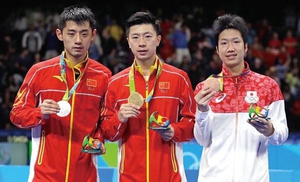 Ma Long, of China, center, holds his gold medal as he stands with silver medalist Zhang Jike, of China, left, and bronze medal winner Jun Mizutani, of Japan, right, after the men's table tennis gold medal match at the 2016 Summer Olympics in Rio de Janeiro, Brazil, Thursday, Aug. 11, 2016. (AP Photo/Petros Giannakouris)